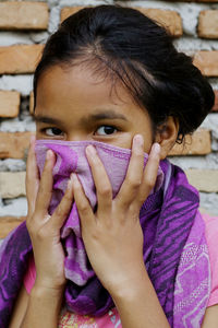 Close-up portrait of girl covering face with scarf