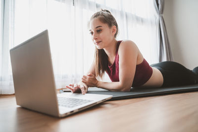 Young woman using mobile phone while sitting on table