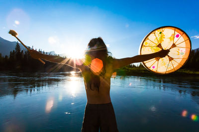 Man standing by lake against sky during sunset