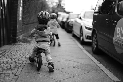 Rear view of boy riding motorcycle on footpath in city