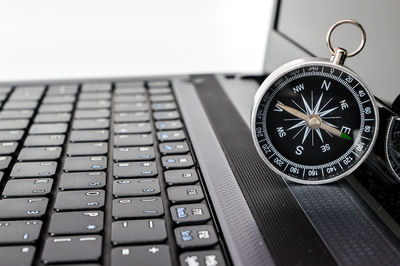 Close-up of navigational compass on laptop against white background