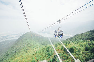 Overhead cable car over mountains against sky