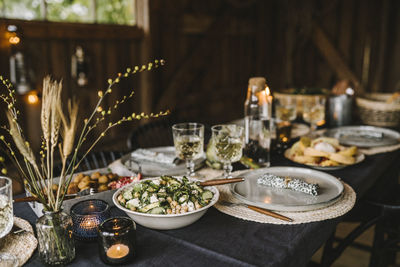 Food in bowl by plate and drinking glass arranged on dining table during social gathering