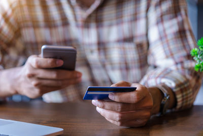 Midsection of man using mobile phone on table