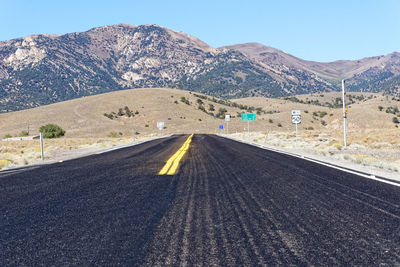 Road leading towards mountains against sky