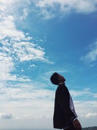 Low angle view of man with closed eyes standing against sky