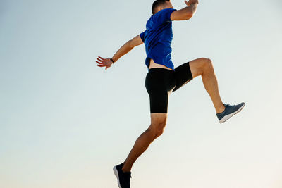 Low angle view of man jumping against clear sky at sunset