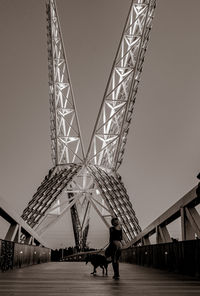 People walking on bridge against clear sky