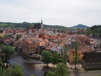 Houses by river in town against sky