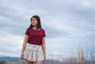 Young woman standing against sky