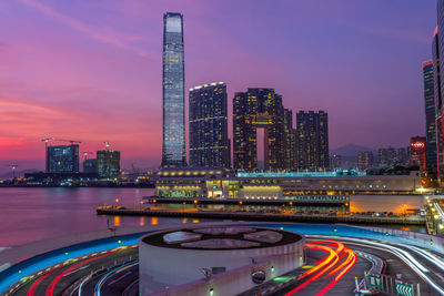 Illuminated modern buildings in city against sky at night