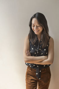 Smiling young woman standing against wall