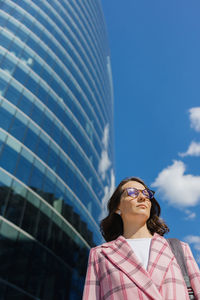 Portrait of young woman standing against sky