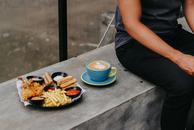 Midsection of man with coffee cup on table