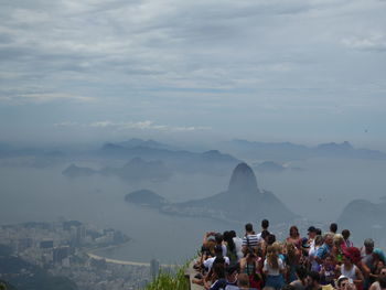 People on mountain against cloudy sky