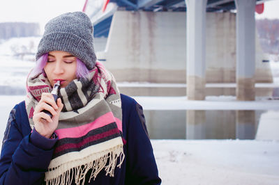 Young woman smoking electronic cigarette during winter