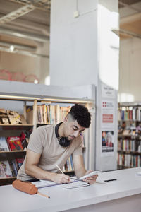 Male student taking notes in library