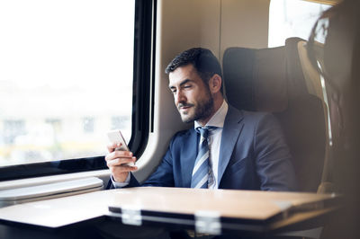 Businessman using smart phone while traveling in train