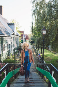 Woman walking on walkway by trees