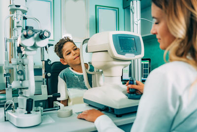 Boy looking at ophthalmologist at clinic