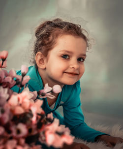 Close-up of cute smiling girl by flowers on rug