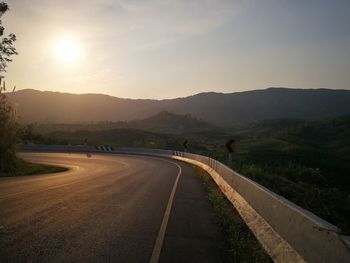 Road leading towards mountains against sky during sunset