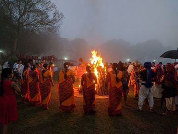 People around bonfire during event at night