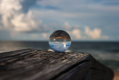 Close-up of crystal ball on sea against sky