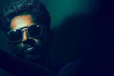 Close-up portrait of young man wearing sunglasses against wall