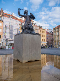 Statue against buildings in city against sky