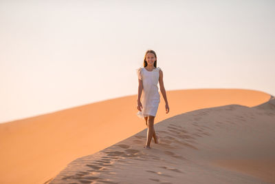 Full length portrait of a smiling young woman on sand