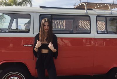 Full length portrait of woman standing on red bus