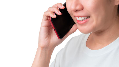 Midsection of woman holding smart phone over white background