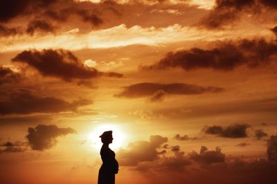 Silhouette man standing against orange sky