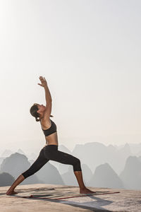 Man with arms raised against mountains against sky