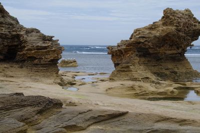 Rock formation on beach against sky