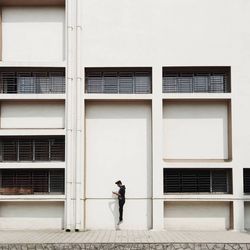 Full length side view of man walking on footpath against building