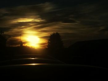 Road amidst silhouette trees against sky at night