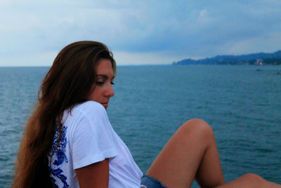 Portrait of woman sitting on beach against sky