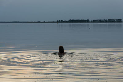 Silhouette person swimming in sea against clear sky
