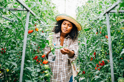 Young woman standing against plants