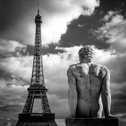 Low angle view of male sculpture in front of eiffel tower against sky