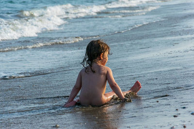 Naked girl sitting in sea