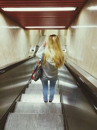Rear view of woman standing on escalator