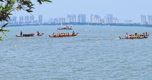 People on boats in sea against sky