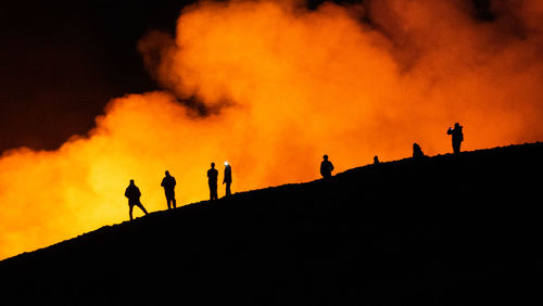 Silhouette people standing against sky during sunset