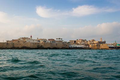 Buildings by sea against sky