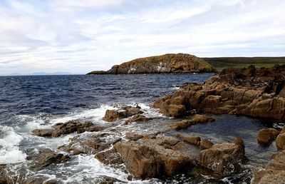 Scenic view of rocks in sea against sky