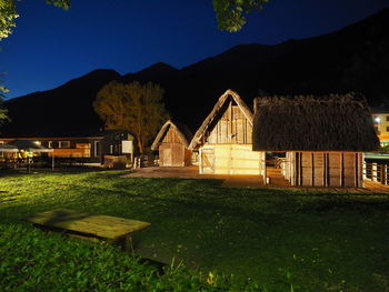 Scenic view of field by houses against sky at night