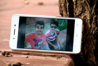 Mobile phone with photograph of young friends sitting on retaining wall